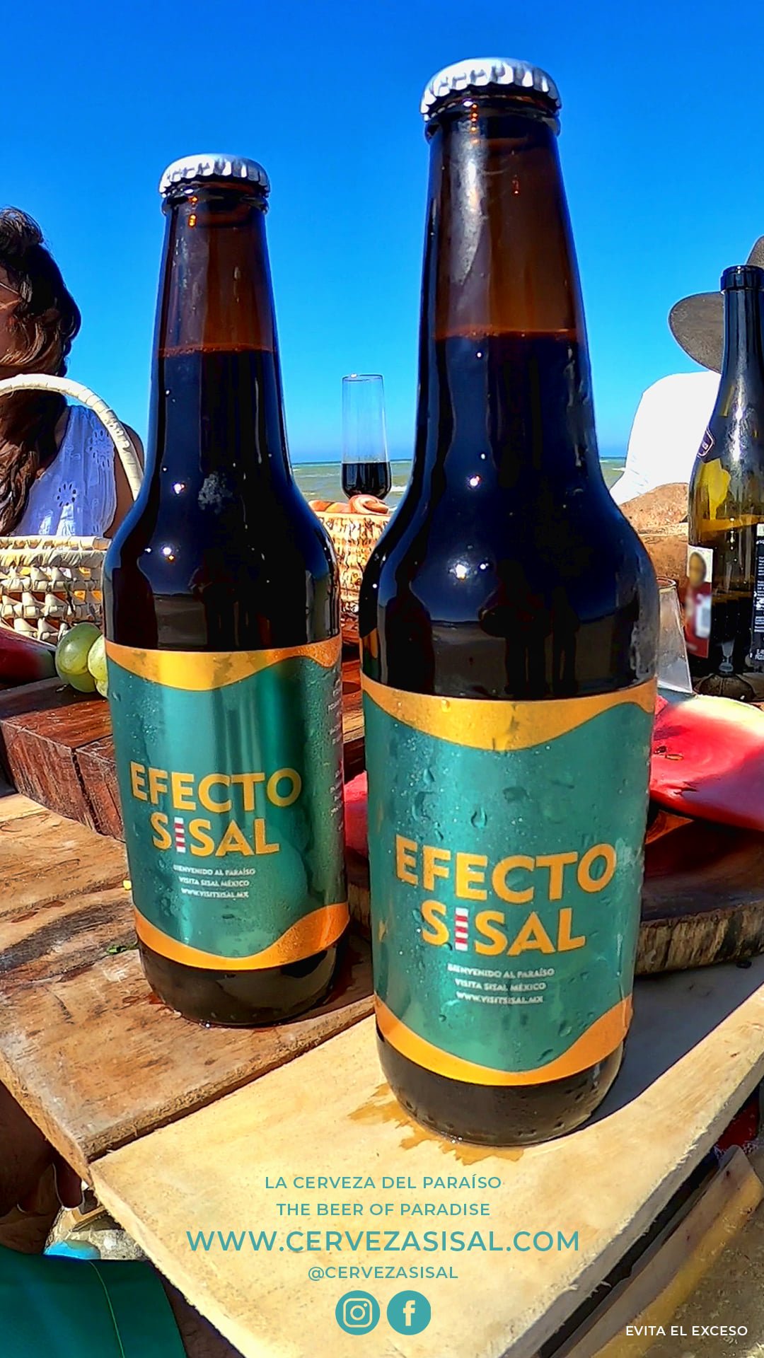 Dos botellas de Cerveza Sisal sobre una tabla de madera en la playa