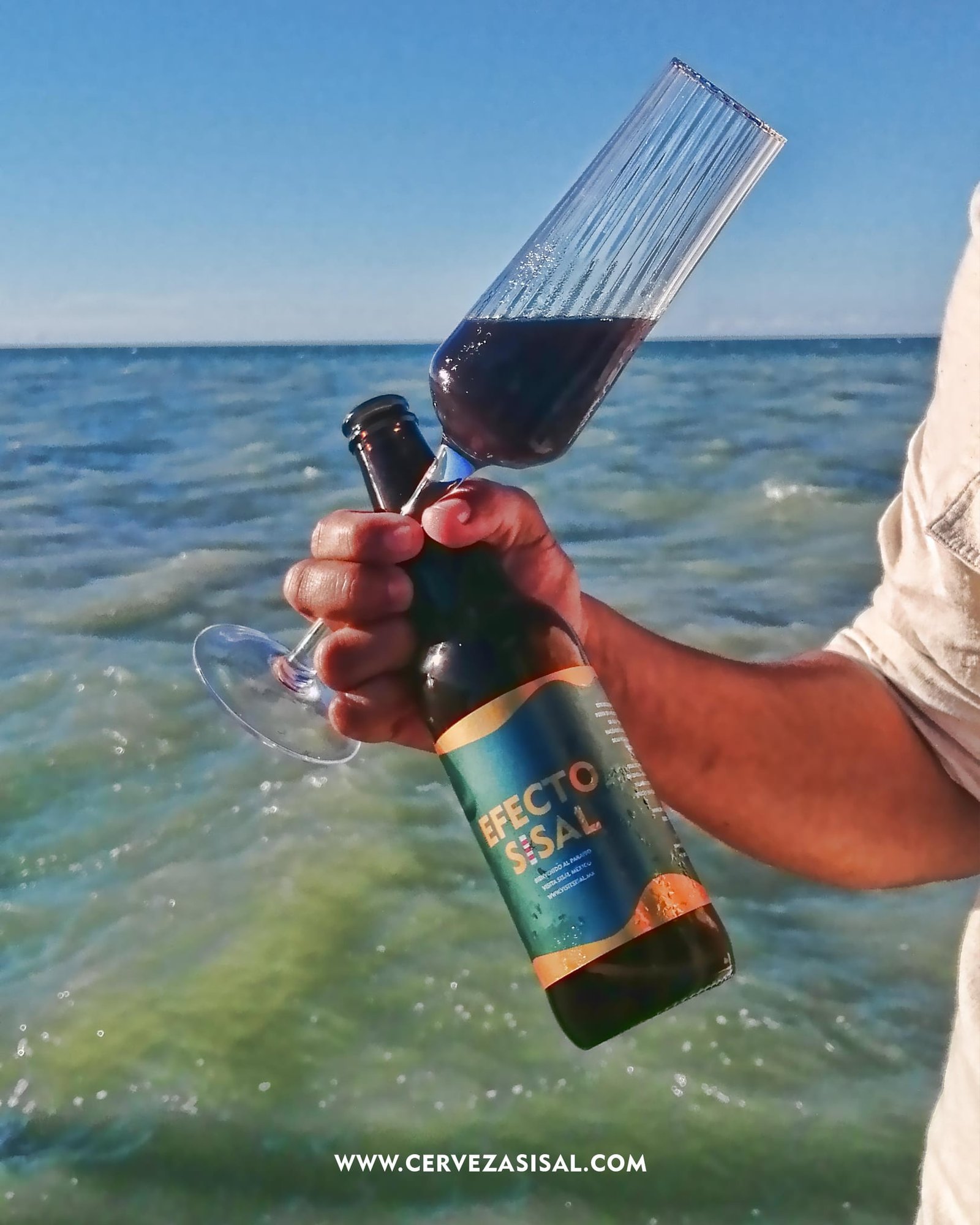 Cerveza Sisal servida en copa frente al mar turquesa de Sisal